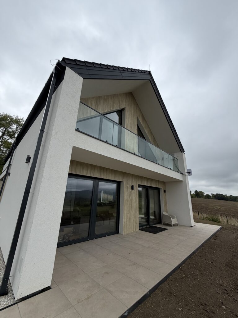 Nowoczesny dom w stylu stodoły z balkonem ze szklaną balustradą nad tarasem