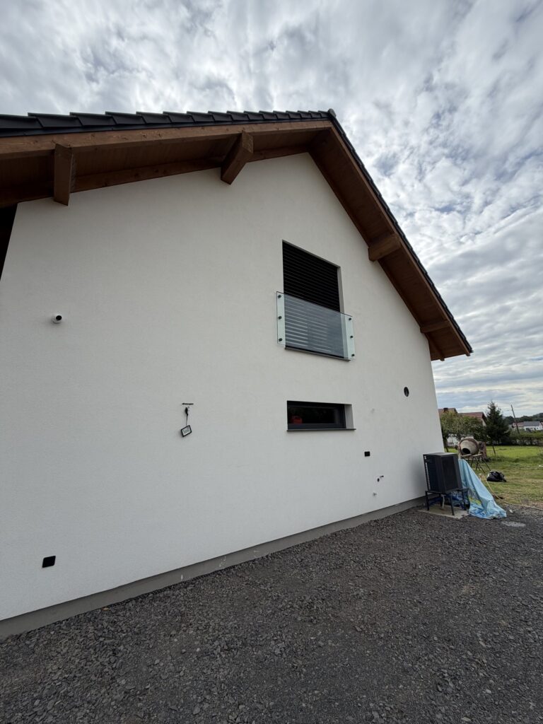 Szklany balkon francuski przy oknie na piętrze, ściana szczytowa domu jednorodzinnego