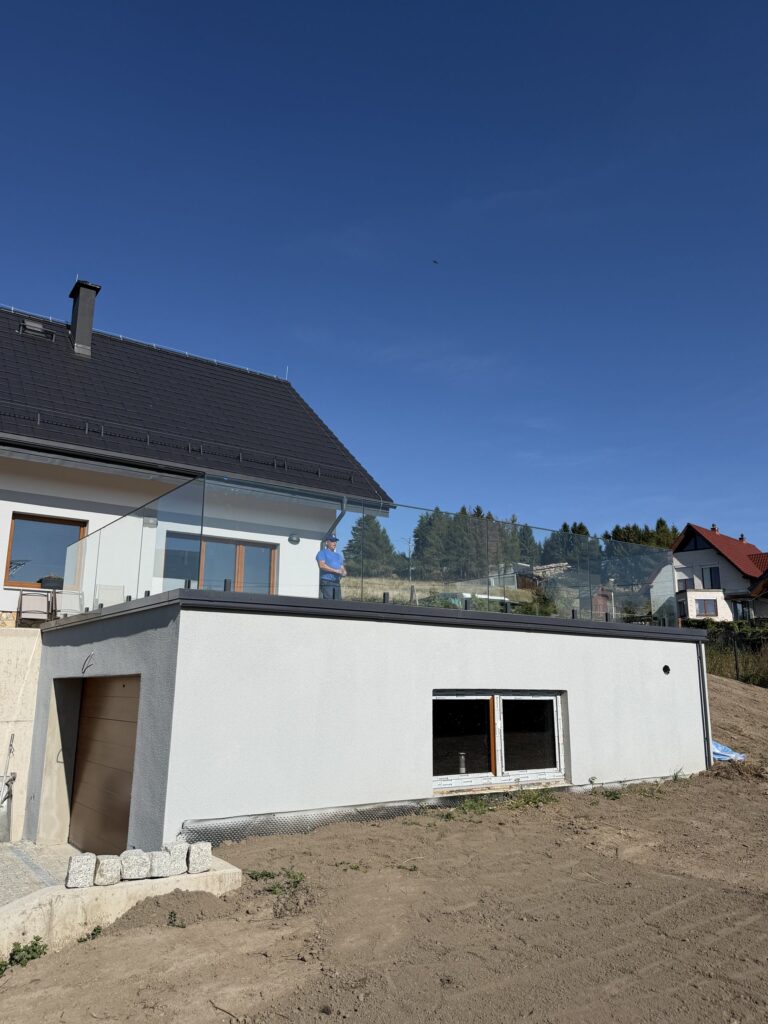 Szklana balustrada na krawędzi tarasu na płaskim dachu, widok z boku budynku